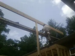 Carpenter setting a ridge beam over a new addition frame — Ice Dam Removal by Roofing Brothers in Prospect